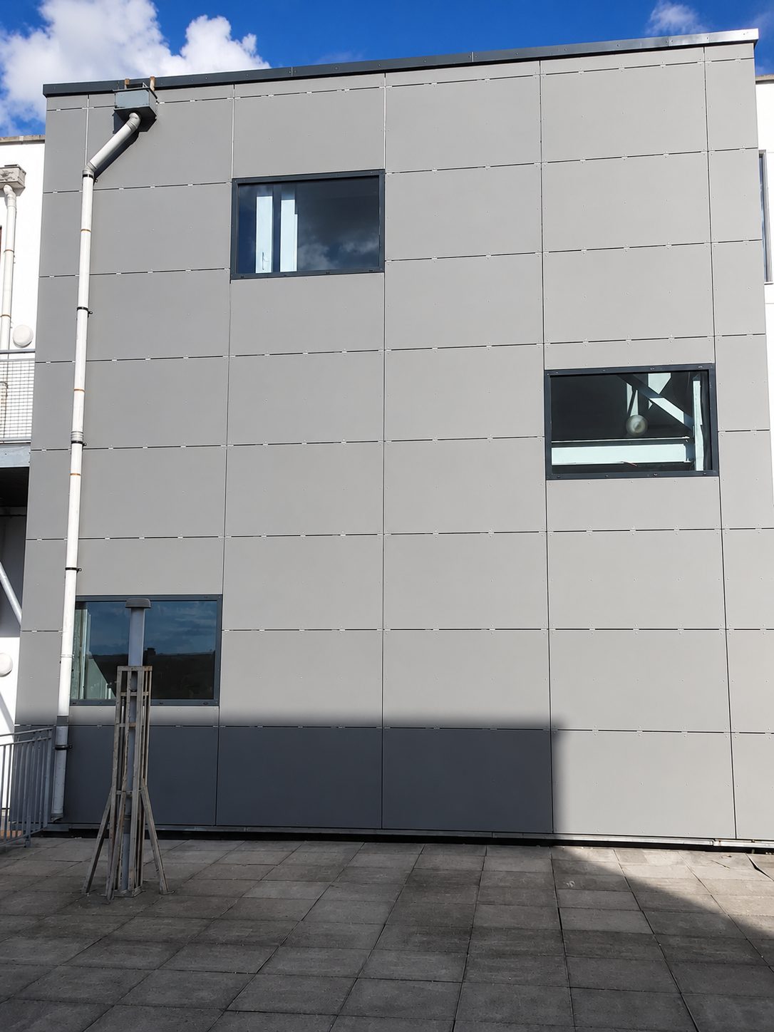 Grey rainscreen panels fitted in a jointed grid at Ability Plaza, with windows set at different heights