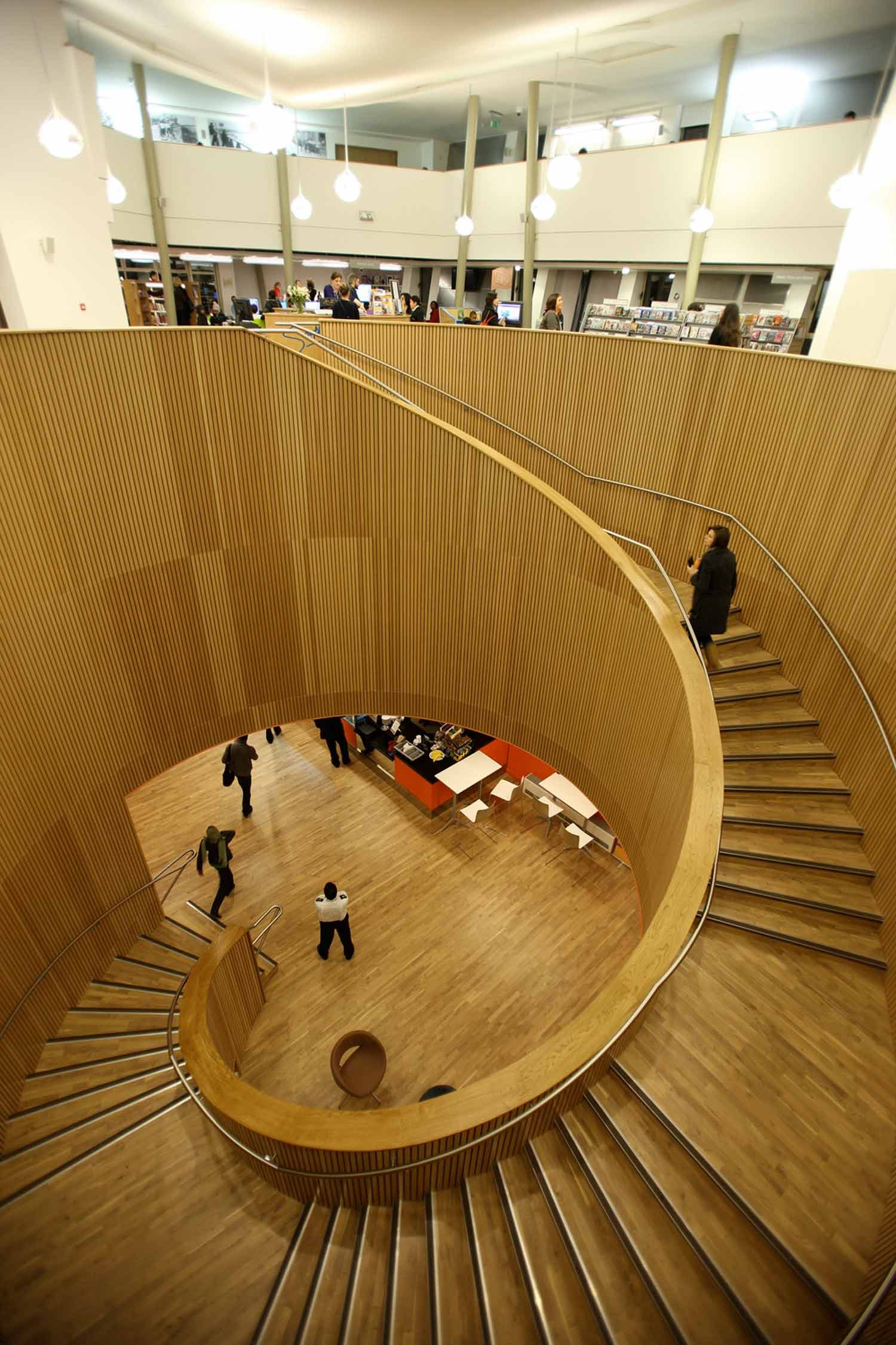 Canada Water Library's helical stair, looking down past oak-lined walls towards the entrance hall