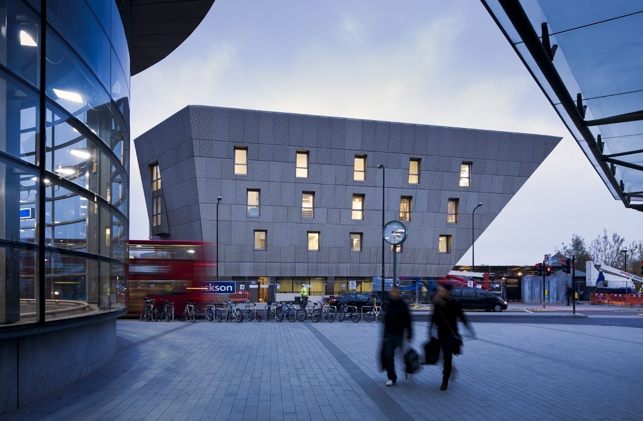 Canada Water Library at dusk, viewed across the square past a curved glazed frontage